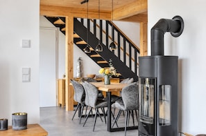 Un intérieur moderne comprenant un coin repas, un poêle noir et un escalier en bois.