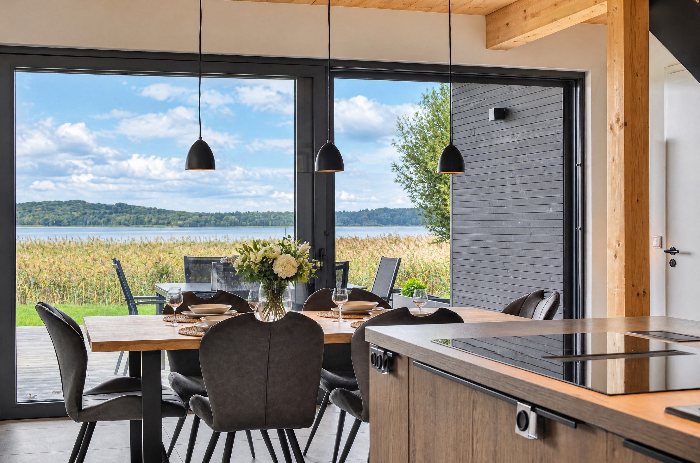 A modern kitchen with a large dining table, chairs, and pendant lights.