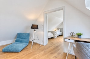 Une chambre à coucher moderne avec un lit en mezzanine, un bureau, une chaise et une lampe sur pied.