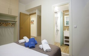 Une chambre d’hôtel avec un lit, une salle de bain avec douche et un couloir avec une porte donnant sur une autre chambre.