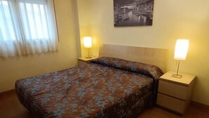 A single bed with a floral bedspread, two bedside tables with lamps, a nightstand, and a wall-mounted picture. - Bilbilis de Mundobriga (Calatayud)