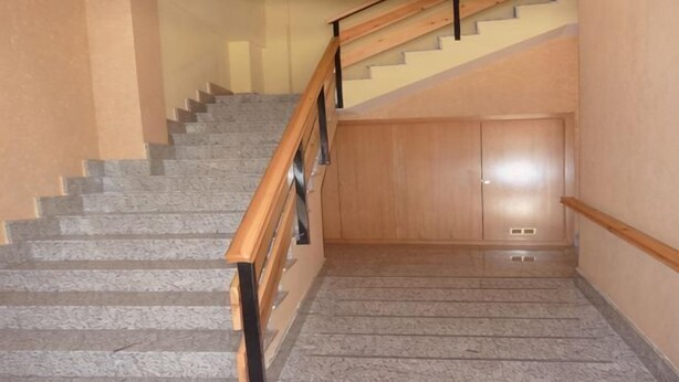 A staircase with wooden handrails, carpeted steps, and a wall with a door at the bottom. - Bilbilis de Mundobriga (Calatayud)
