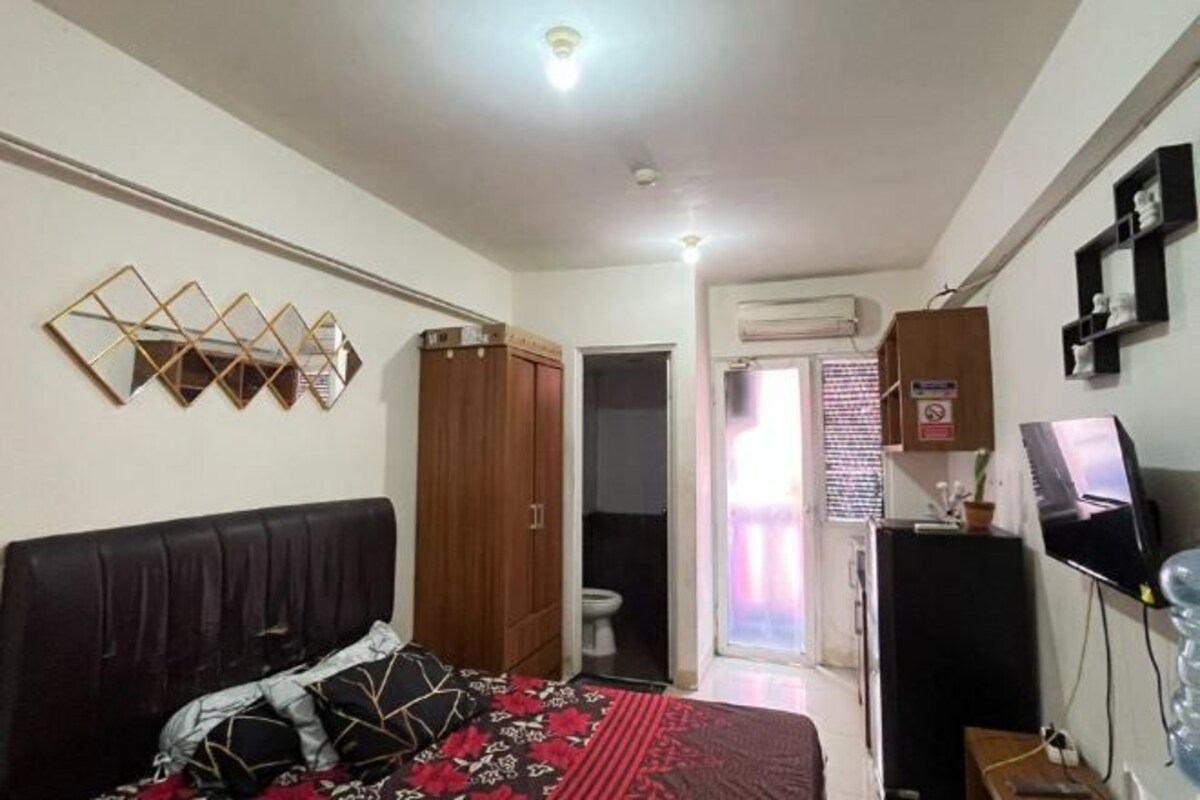 A bedroom with a bed, wardrobe, and a television.