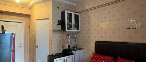 A bedroom with a bed, a wardrobe, a small desk, and a cabinet.