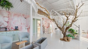 Una habitación amplia con un gran árbol, una escalera y un área de descanso con una mesa de centro.