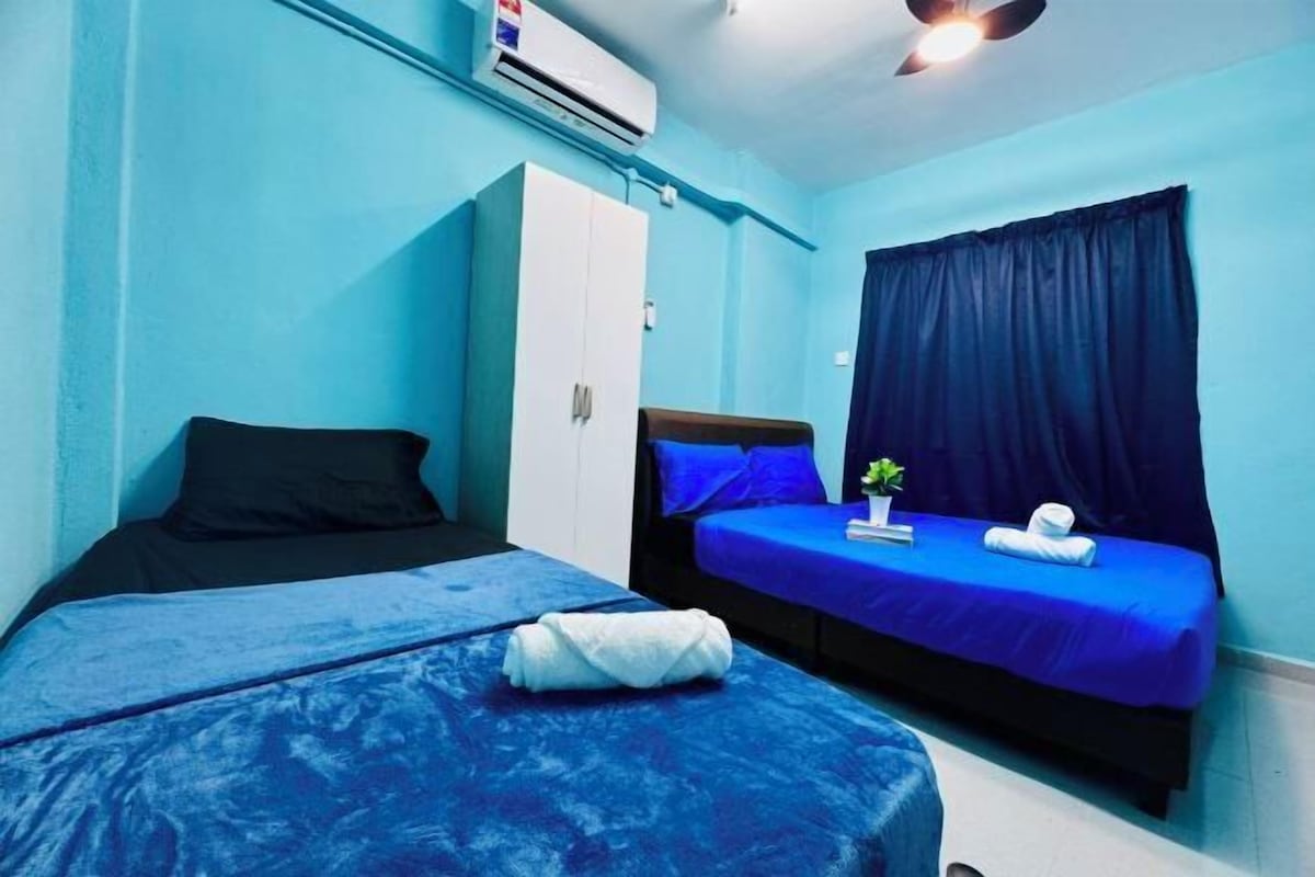 A room with two beds, a wardrobe, an air conditioning unit, and a ceiling fan.