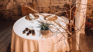 A round table with a white tablecloth, a woven light fixture, a potted tree, and a stone wall in the background. - Apartment 'Suite Romántica' with Mountain View, Wi-Fi and Air Conditioning (Canyelles)
