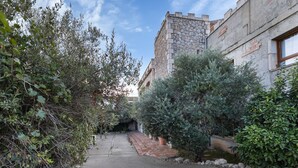 A narrow pathway leading to a stone building with a rustic appearance, surrounded by dense foliage and a clear sky. - Apartment 'Suite Romántica' with Mountain View, Wi-Fi and Air Conditioning (Canyelles)