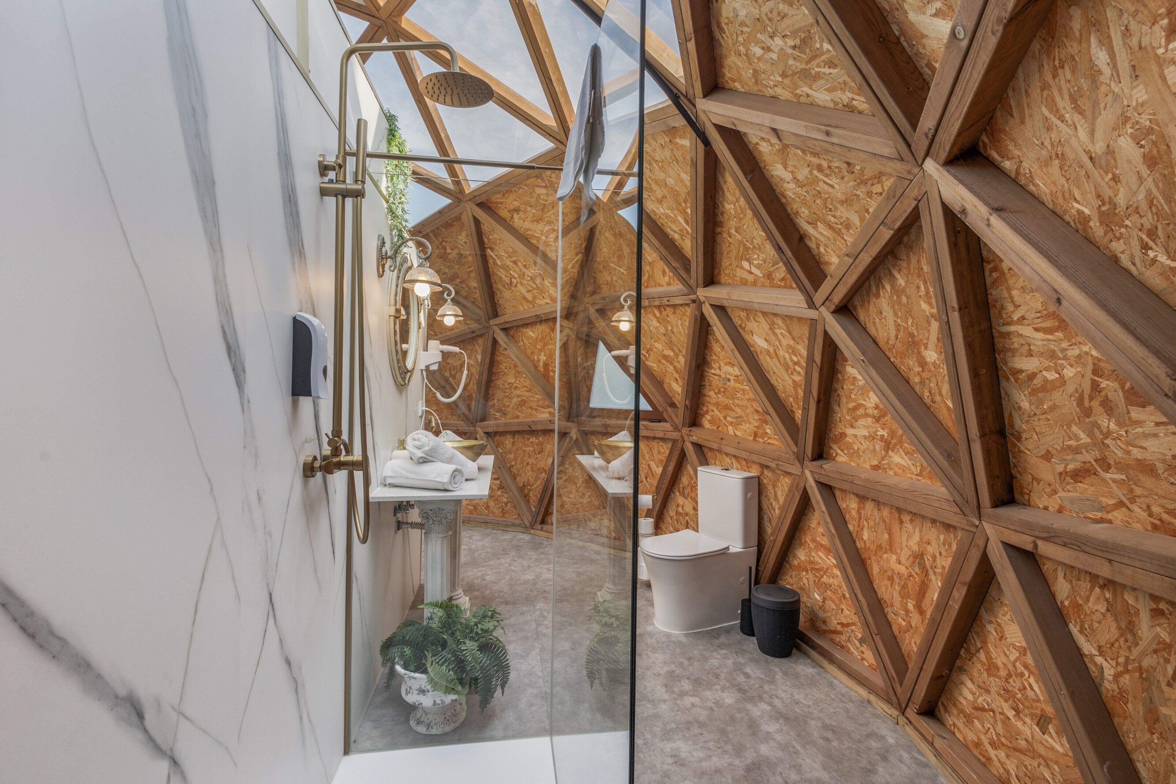 A modern bathroom with a wooden ceiling, a marble wall, a sink, and a toilet.