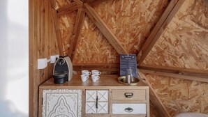 A wooden cabin interior with a coffee station, white drawers, and a menu board.