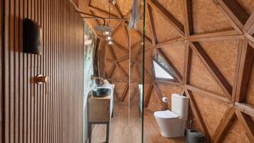 Een kleine, moderne badkamer met een schuine kap, houten lambrisering, een wastafel, toilet en een klein raam.