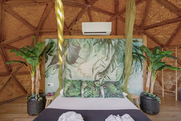 A room with a bed, a mural, and two potted plants.