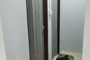Un pasillo estrecho con una puerta a la izquierda y un felpudo estampado en el suelo.