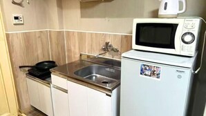 Une cuisine compacte équipée d’un four à micro-ondes, d’un évier et d’un petit réfrigérateur.