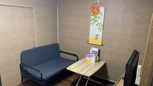 Une petite pièce avec un canapé, une table en bois, un téléviseur et une affiche accrochée au mur.