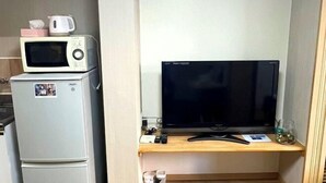 Une petite cuisine équipée d’un four à micro-ondes, d’un petit réfrigérateur et d’un téléviseur à écran plat, le tout installé sur une étagère en bois.