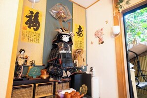 Une pièce de style japonais traditionnel, avec un sol recouvert de tatamis, un paravent shoji et une armure de samouraï exposée.