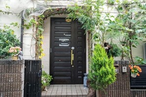 Une porte noire avec une petite fenêtre, un portail et un pot de fleurs.