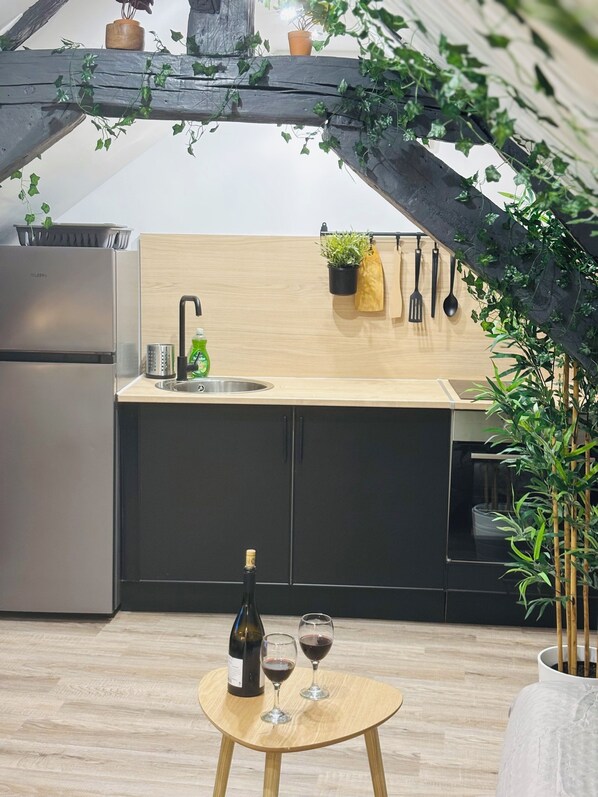 A modern kitchen with a wooden countertop, a sink, and a wine bottle.