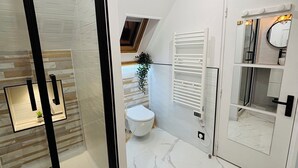 Une salle de bain moderne avec une douche à parois de verre, des toilettes blanches et un meuble-lavabo avec un miroir.
