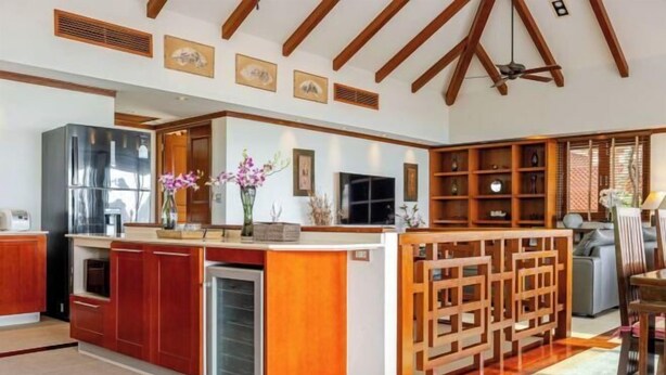 A modern kitchen with wooden cabinets, a built-in refrigerator, and a decorative island. - Patong Seaview Luxury Villa Penda (Phuket)