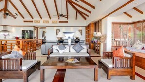 A spacious living area with wooden furniture, a central coffee table, and a kitchen in the background. - Patong Seaview Luxury Villa Penda (Phuket)
