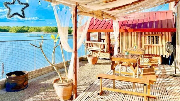An outdoor seating area with wooden furniture and a view of a body of water.