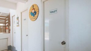 A hallway with a sign for the shower, a sign for the toilet, and a decorative sign with a sun and waves.