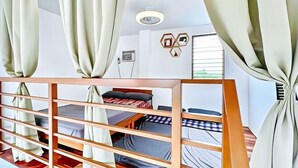 A room with bunk beds, a wooden headboard, a desk, and a window with curtains.