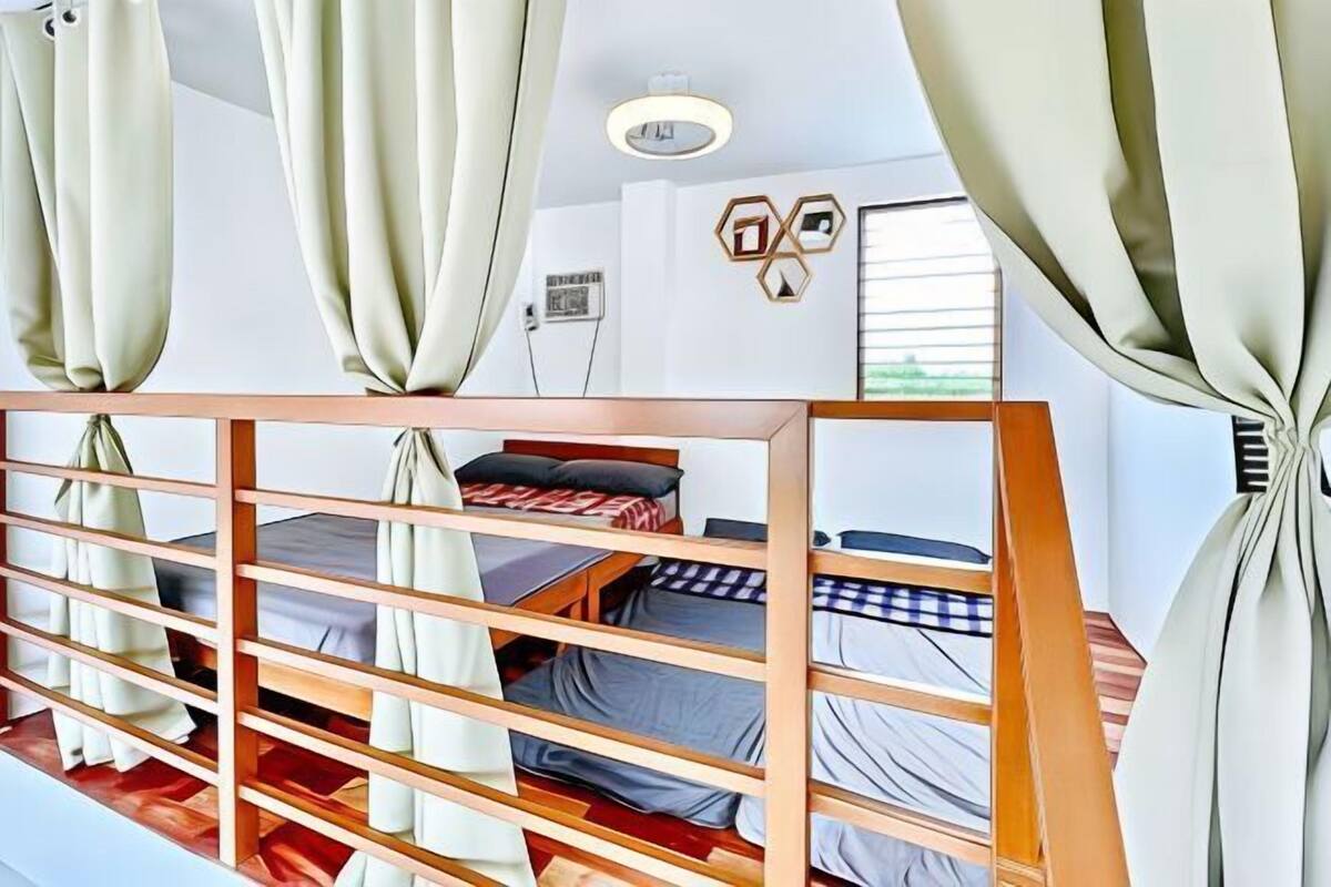A room with bunk beds, a wooden headboard, a desk, and a window with curtains.