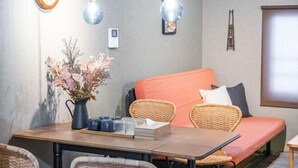 A room with a dining table, wicker chairs, a sofa with cushions, a vase with dried flowers, and hanging light fixtures. - Travel time Momotani - 9min walk to Tōgaku Station, 18min walk to Shitennoji Temple (Osaka)