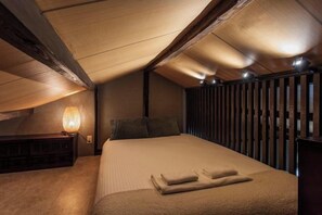 Un dormitorio con cama, mesita de noche, lámpara y listones de madera en la pared.
