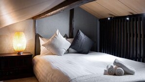 A bedroom with a bed, pillows, a nightstand, a lamp, and rolled towels. - Travel time Momotani - 9min walk to Tōgaku Station, 18min walk to Shitennoji Temple (Osaka)