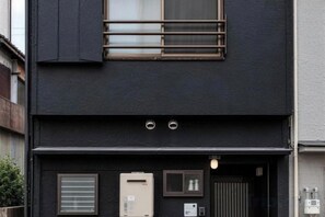 Un bâtiment noir avec une fenêtre, une porte et un appareil de climatisation.