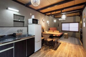 Cocina compacta con microondas, refrigerador y estufa moderna. Cuenta con un comedor con mesa y sillas, además de un amplio ventanal que proporciona luz natural.