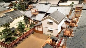 A traditional Japanese-style building with a tiled roof, wooden structures, and a fenced courtyard. - Travel time Momotani - 9min walk to Tōgaku Station, 18min walk to Shitennoji Temple (Osaka)