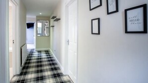 A hallway with a checkered floor, white walls, and framed pictures with text. - Ridgeway Meadow Bungalow - 3 Bedroom - Manorbier (Tenby)