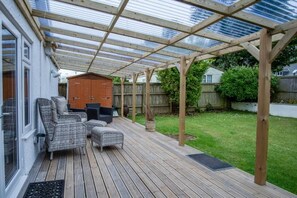 A covered patio area with a wooden deck, outdoor furniture, and a pergola structure. - Ridgeway Meadow Bungalow - 3 Bedroom - Manorbier (Tenby)