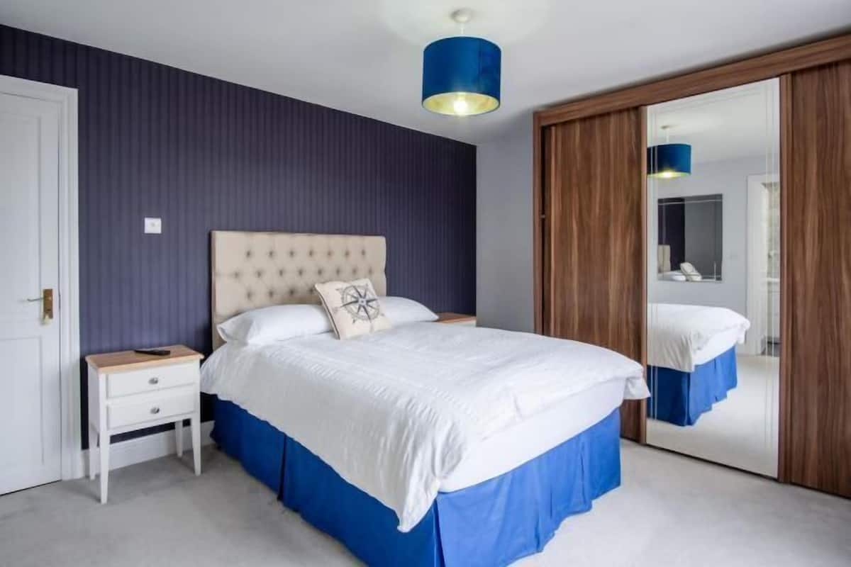 A bedroom with a bed, a nightstand, a mirror, and a wardrobe.