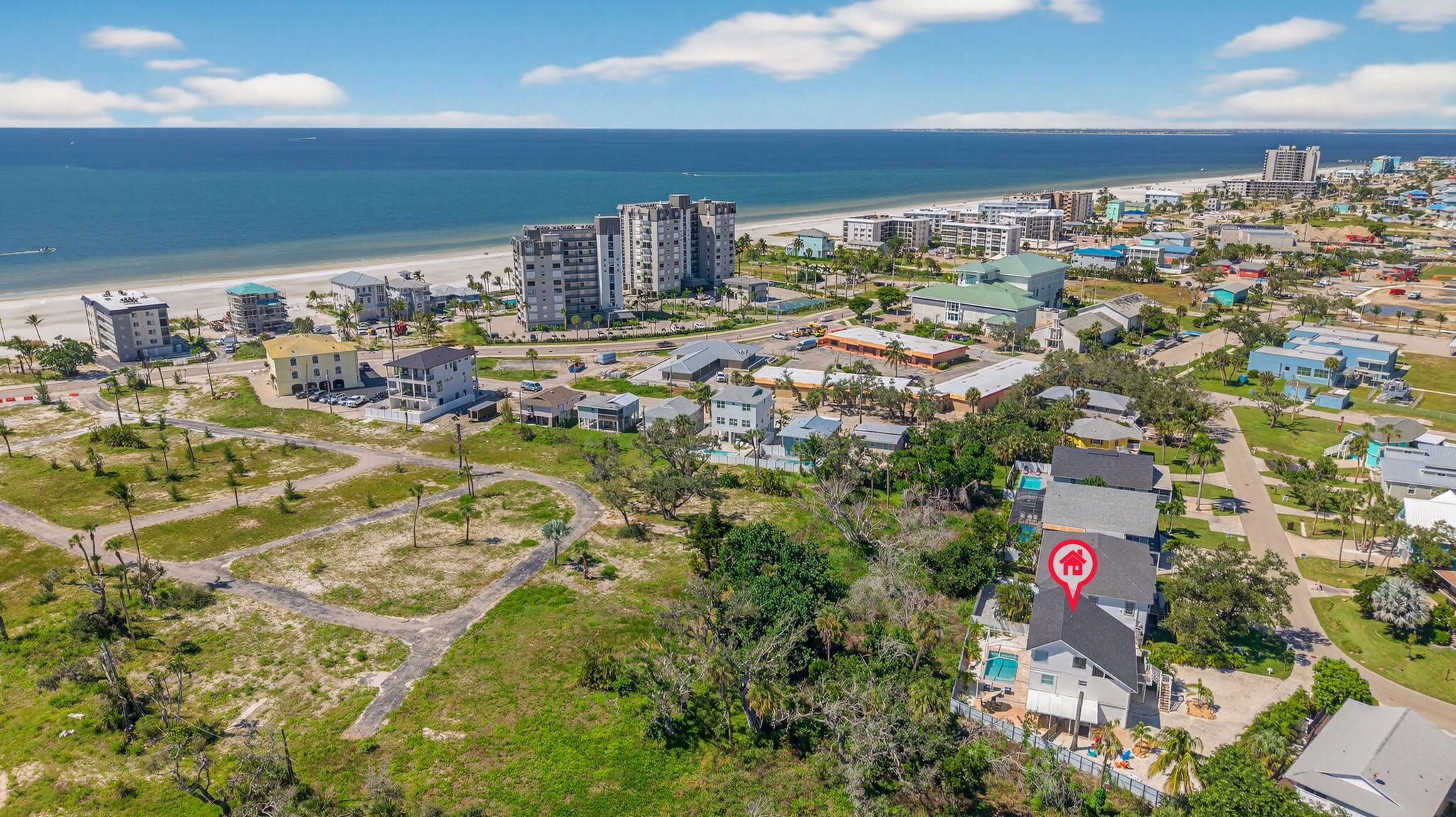 Vue aérienne d’un quartier résidentiel situé sur la côte, avec de nombreux immeubles, une plage et une vue dégagée sur l’océan.