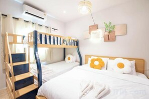 A bunk bed room with a staircase, a bedside table, and a wall-mounted plant.