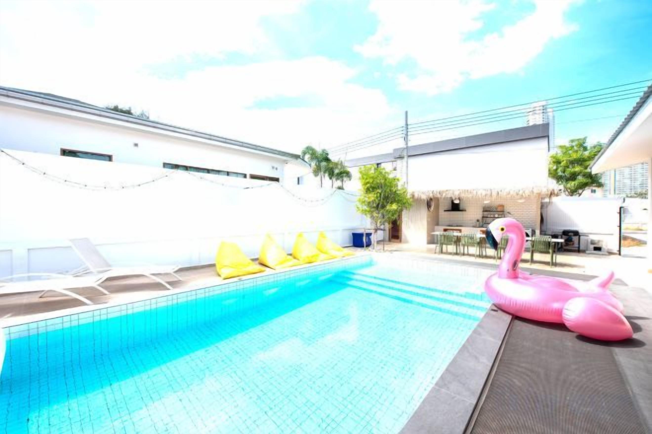 Ein Swimmingpool mit Liegestühlen und einem Flamingo-Schwimmpferd.