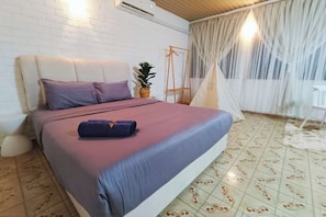 Un dormitorio con una cama, una planta colgante, un columpio de madera y una tienda de campaña.