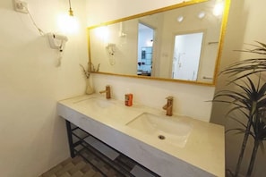 Baño con dos lavamanos, un espejo y un secador de pelo en la pared.