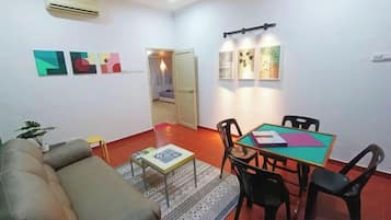 Una sala de estar con un sofá, una mesa de comedor con sillas y una alfombra pequeña.
