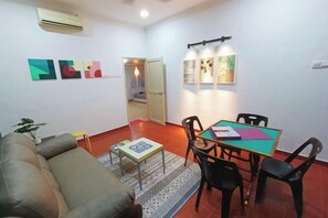 Una sala de estar con un sofá, una mesa de comedor con sillas y una alfombra pequeña.