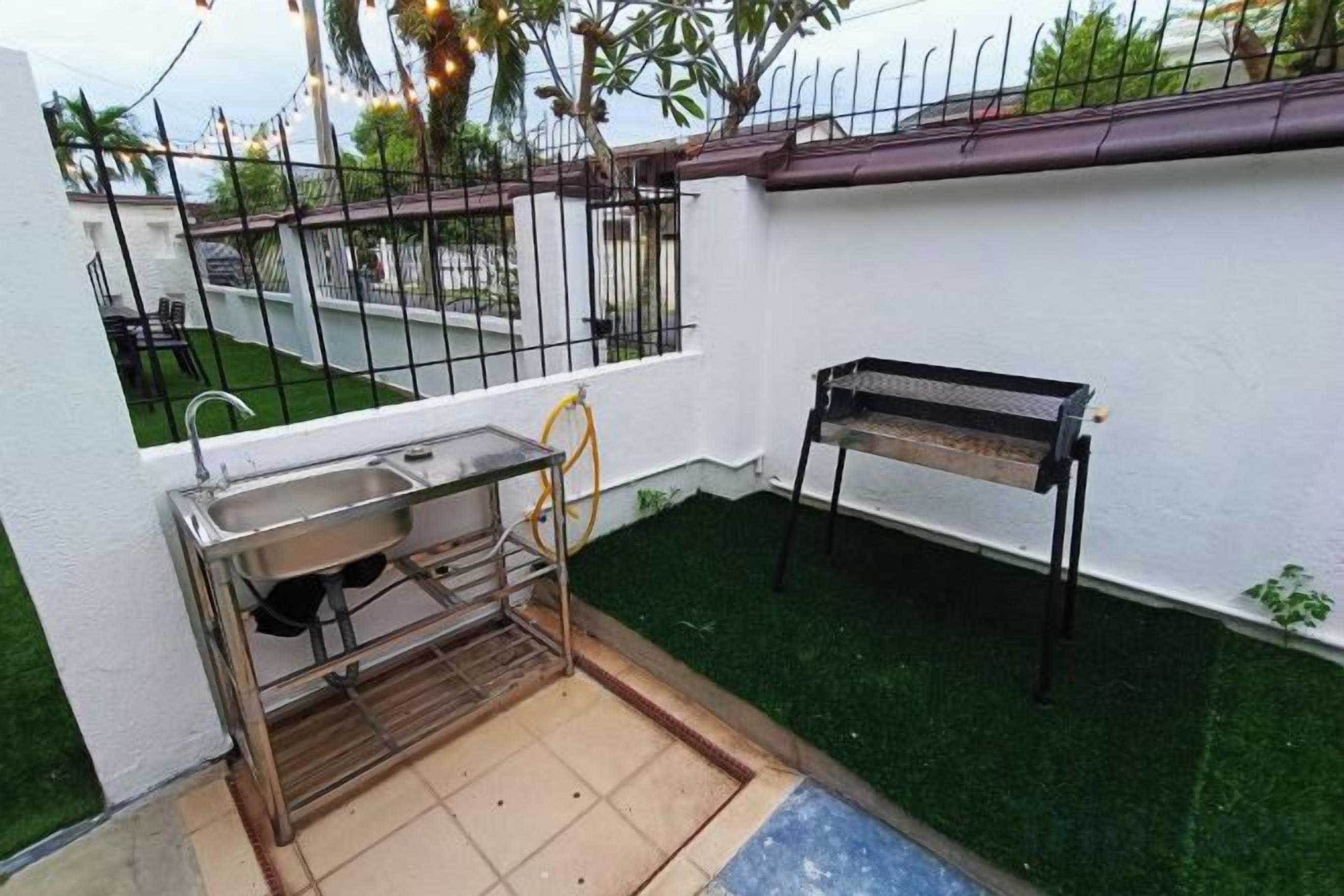 Un pequeño espacio de cocina al aire libre con pileta, banco y césped artificial.