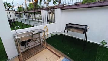 Un pequeño espacio de cocina al aire libre con pileta, banco y césped artificial.