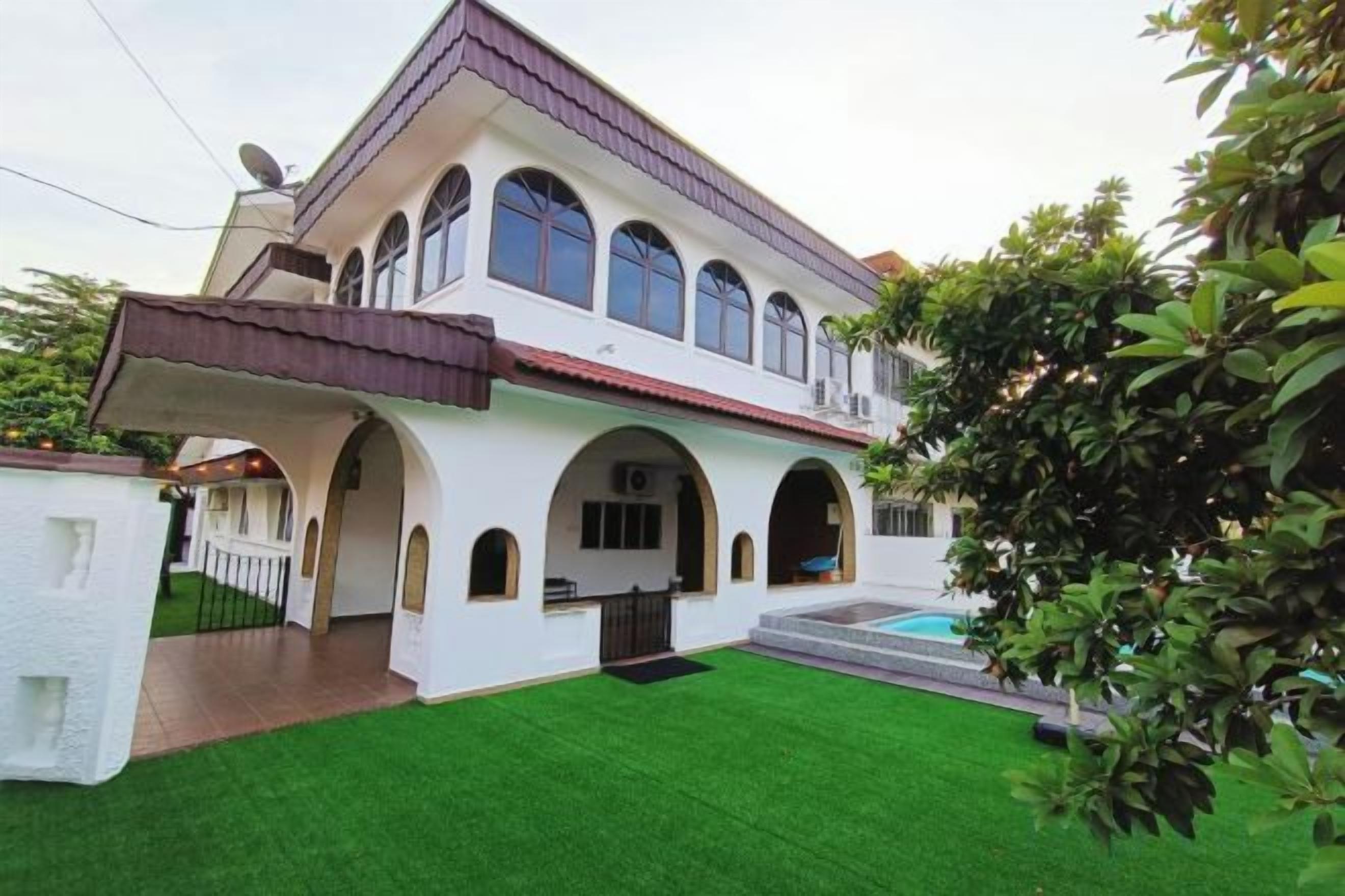 Una casa de dos pisos con un porche cubierto y una piscina.