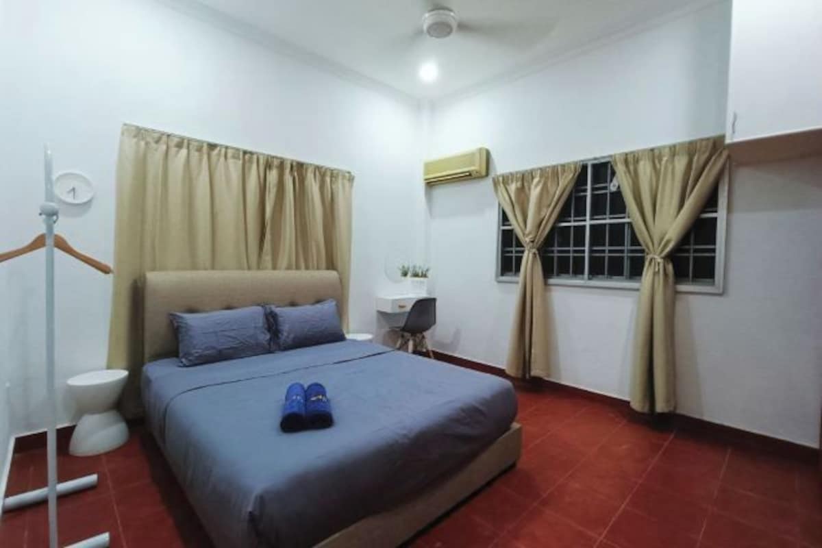 Un dormitorio con cama, escritorio, aire acondicionado y cortinas.